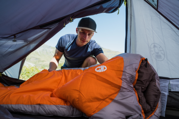 Young man preparing a Silverton Sleeping bag in a tent.